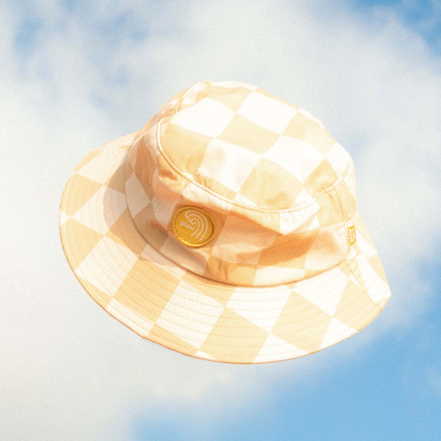 Checkered bucket hat against a blue sky with clouds